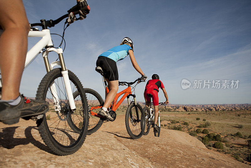 三个骑自行车的人在滑岩小道上骑山地车
