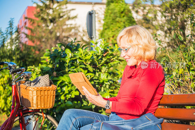 老年妇女在户外使用平板电脑