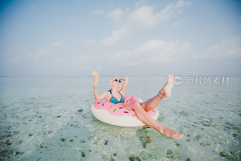 性感的女人浮在水上，有鸡尾酒时间在海洋，马尔代夫