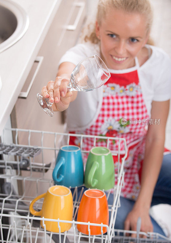 拿着酒杯在洗碗机上方的女人
