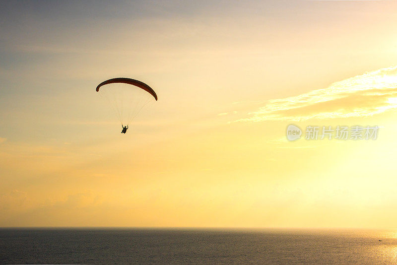 泰国普吉岛，在夕阳下，滑翔伞飞跃大海的剪影。