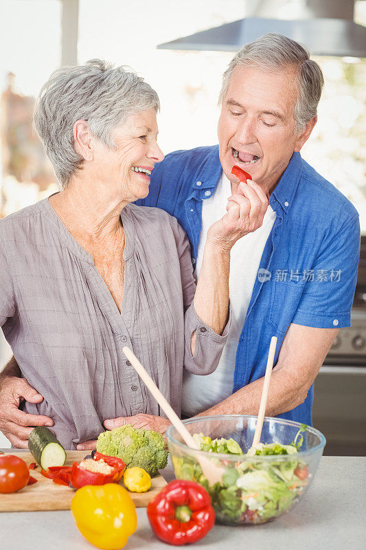 快乐的老妇人一边站在柜台边喂丈夫