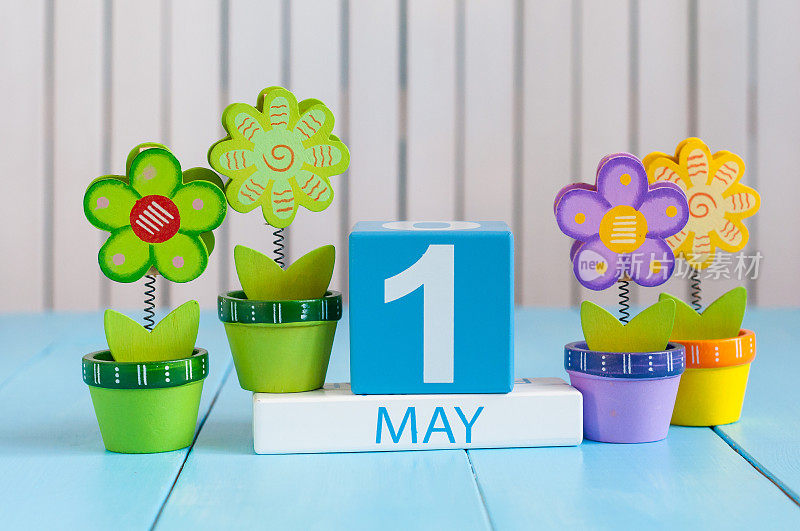 5月1日。5月1日的图片木制彩色日历在白色的背景与鲜花。春日，空为文字。国际劳动节
