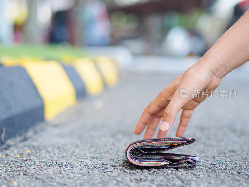 一个女人捡起路边掉落的钱包的特写