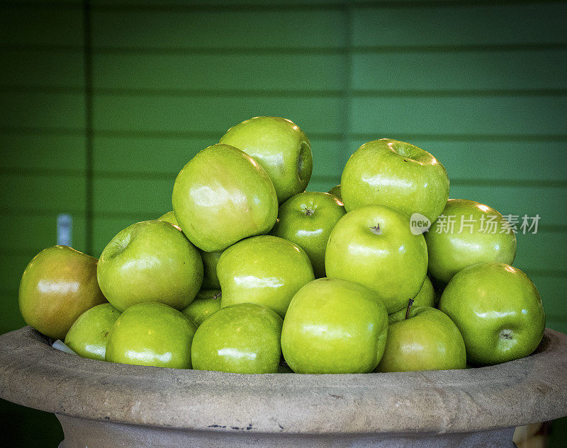 一碗“绿铁匠”苹果靠在一堵绿墙上。