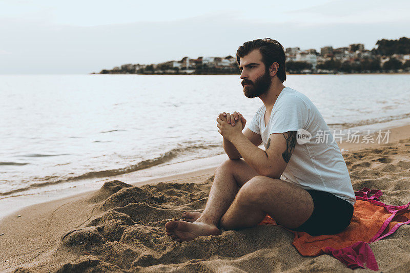 帅哥在沙滩上放松，欣赏风景