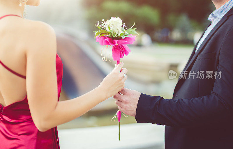 一位时髦的年轻人送给一位女士一朵装饰精美的花。