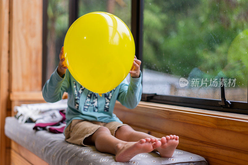 孩子用爱的表情气球遮住脸。