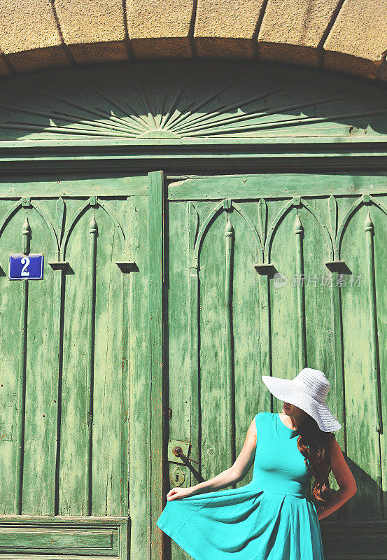 戴着帽子的女人在一扇绿色的门前跳舞