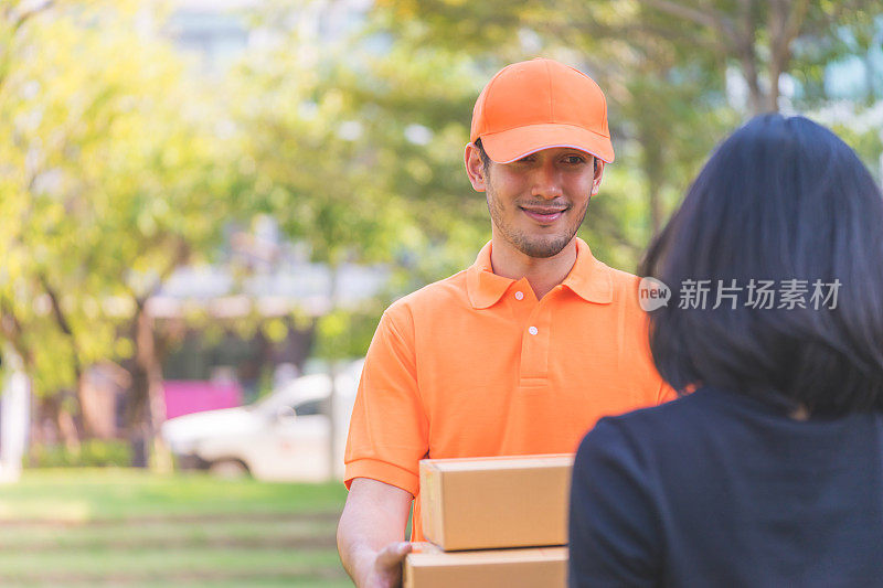 穿橙色衣服的快递员正在给一位女士递包裹