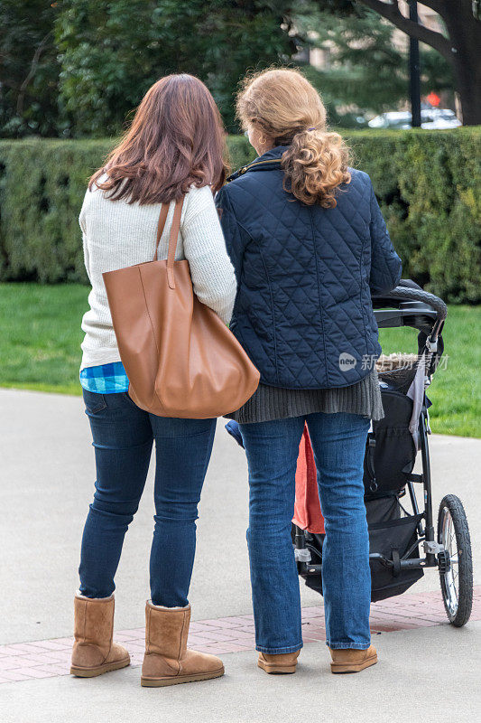 成熟的女人身后推着婴儿车