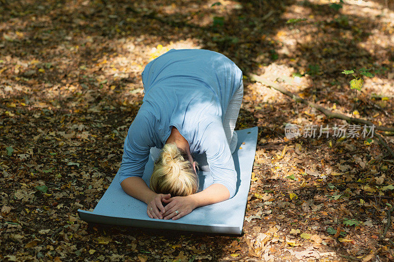 健康怀孕:金发女人在森林户外练习瑜伽