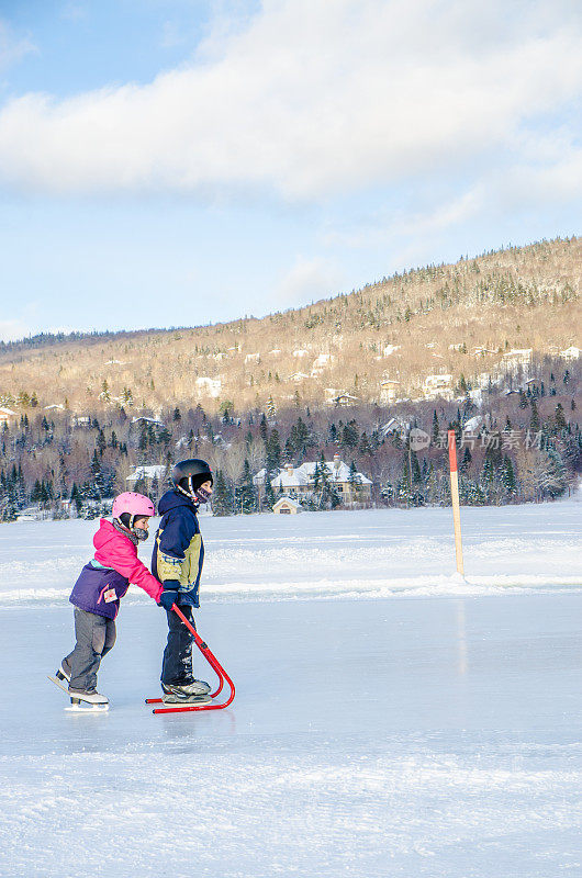 哥哥和姐姐在冬季在博波特湖镇的湖面上滑冰