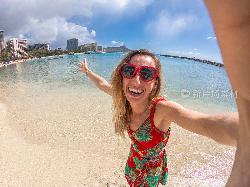 一名年轻女子戴着红色心形太阳镜在夏威夷檀香山的怀基基海滩自拍
