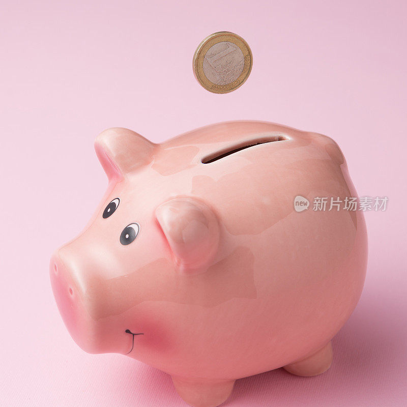 一枚欧元硬币掉进了一个存钱罐，特写，背景是粉红色，金融概念