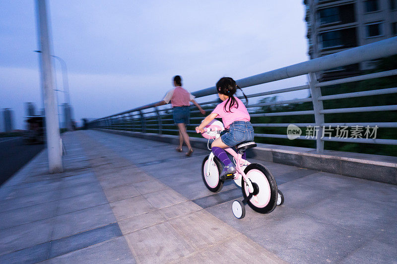 一个年轻的女孩在路上骑自行车