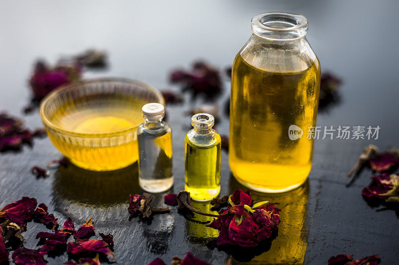 靠近蓖麻油，茶树油，和一些椰子油的瓶子在木制表面，以及一些原始蜂蜜和玫瑰花瓣也出现在表面。