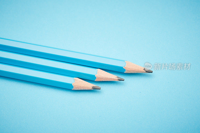 三支蓝色铅笔从左边进入画框