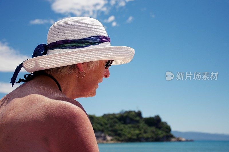 夏日沙滩上戴太阳帽的资深女士