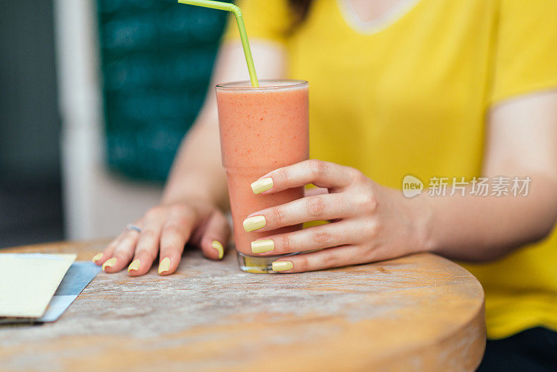 在街头酒吧拿着一杯水果冰沙的女人