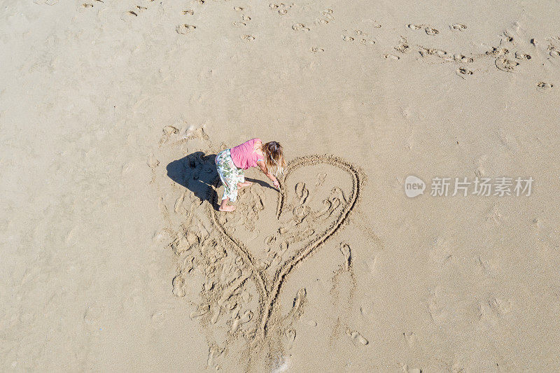 无人机的观点，年轻女子在海滩上画心