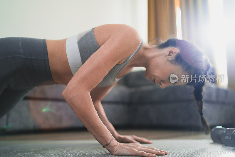 美丽健康的女人在家里做瑜伽。