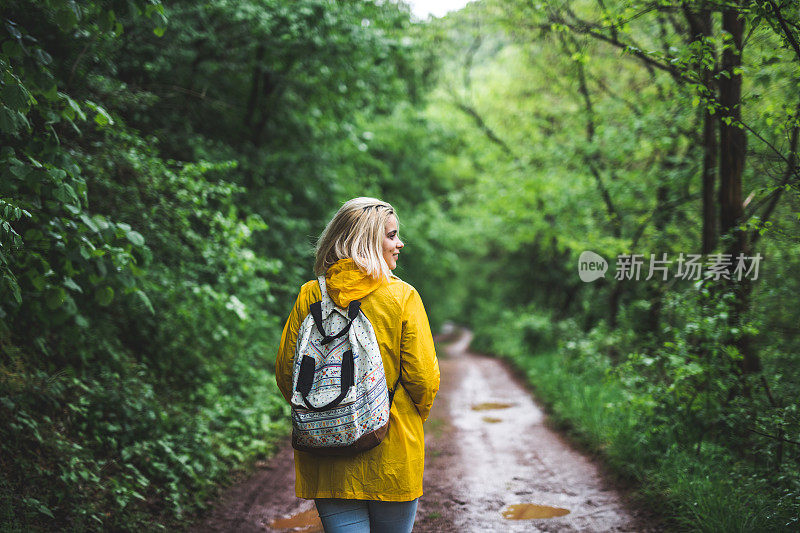 微笑的年轻女子在森林里走在雨衣