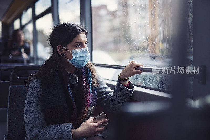 在公共汽车上戴着防护口罩的女人。