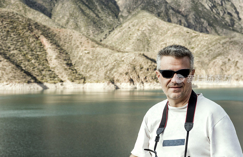 英俊的摄影师在安第斯山脉的波特雷洛斯湖前摆姿势。阿根廷门多萨。