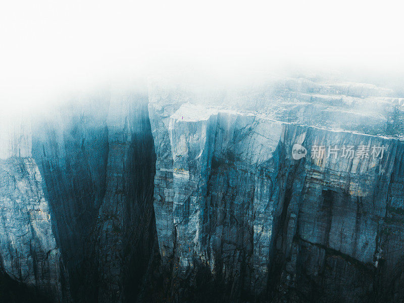 鸟瞰图一个徒步旅行者停留在大悬崖的边缘在挪威的穆迪日出