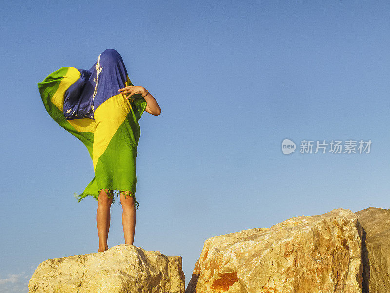 一个学龄前女孩在海滩上举着巴西国旗