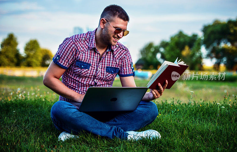 学生用笔记本电脑搜索信息，在大学公园看书。教育、生活方式的概念