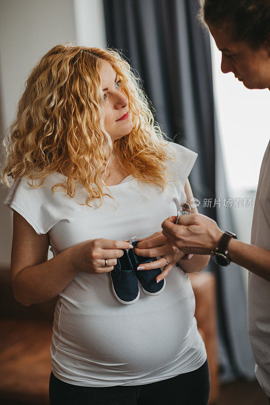 一对抱着婴儿鞋的怀孕夫妇