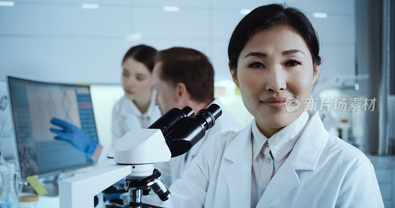 基因研究实验室内部。亚洲女医生使用显微镜