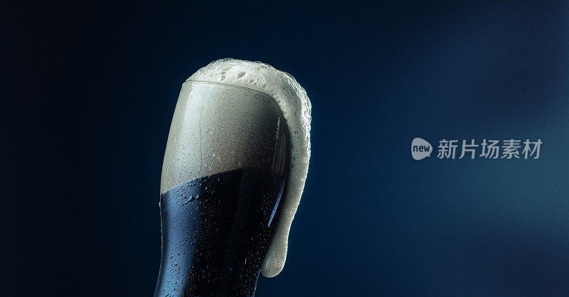 将冰凉清爽的啤酒倒进有泡沫的玻璃中，水平放置