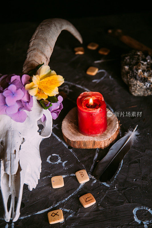 有角的白色山羊桨，鲜花，打开的旧书，女巫桌上的蜡烛。