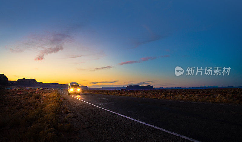 黄昏时分，商业货车在亚利桑那州纪念碑谷的乡村道路上行驶