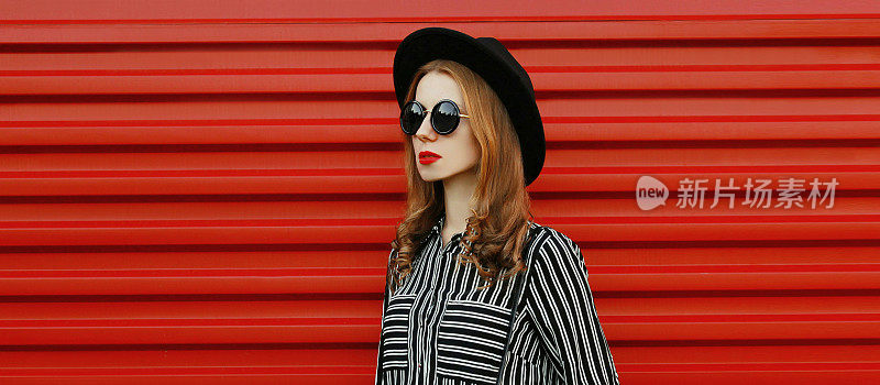 肖像的年轻女子模特身穿黑白条纹衬衫，圆帽子越过红色墙的背景
