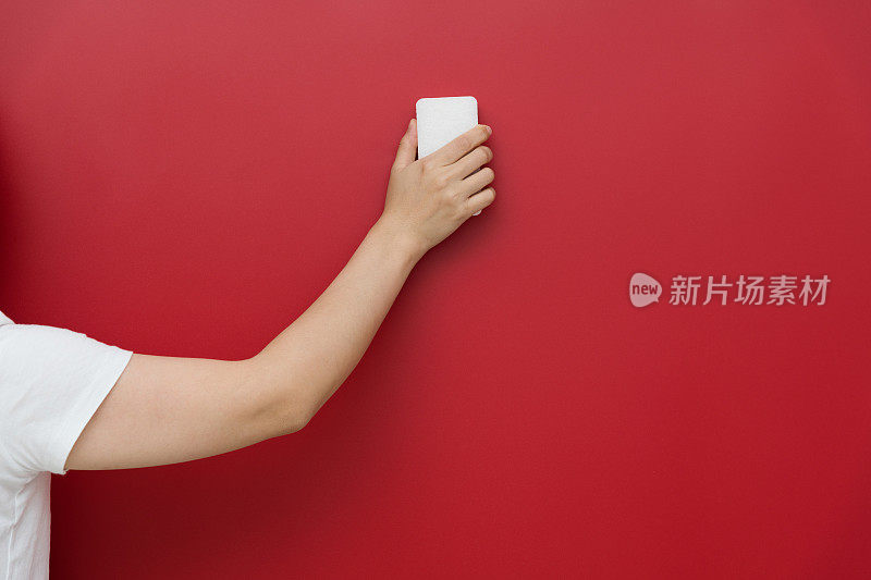 女人用海绵擦拭红色的墙壁