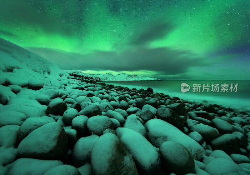 海洋上空的北极光。俄罗斯捷里别尔卡的北极光。星空，极地的光和云。夜晚冬天的景观与明亮的极光，星星，大海，雪石在模糊的水。旅行