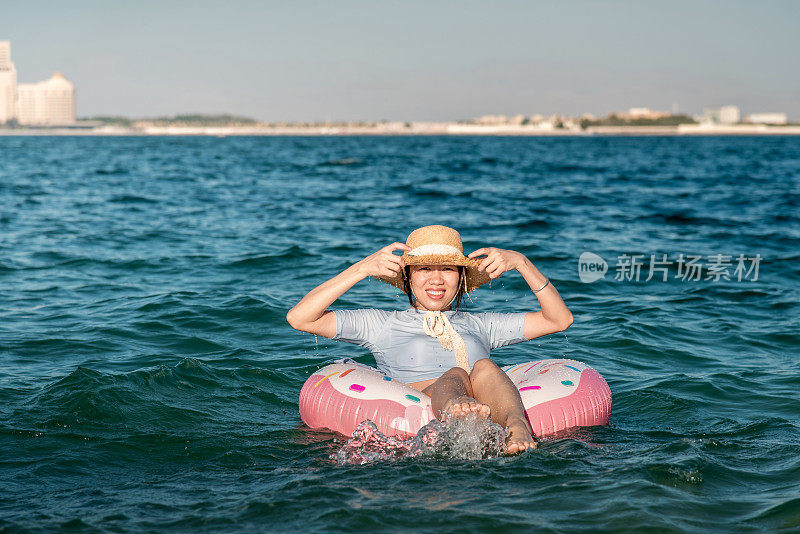 女人游泳和漂浮在海边的水与甜甜圈浮