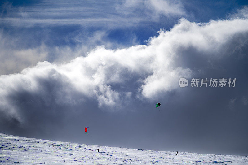 两只雪风筝在雪坡上，在云的前面