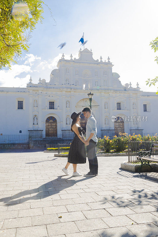 一对西班牙夫妇在危地马拉安提瓜的圣何塞大教堂前见面——年轻的游客们在阳光明媚的日子里享受着他们在这座殖民城市的假期——危地马拉安提瓜的中央公园