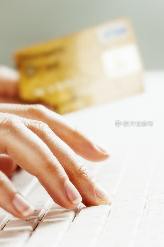 网上购物或网上银行:女人的手拿着信用卡在电脑上打字