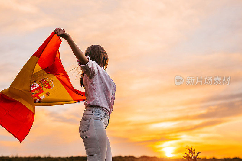 日落时分，一名女子在西班牙国旗下伸展