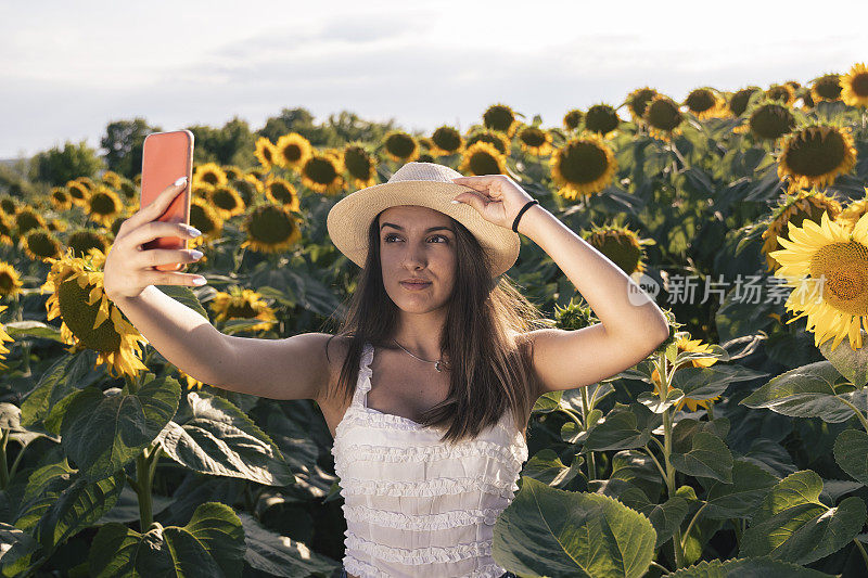 一个年轻女孩在盛夏的向日葵上自拍。青少年的精神。生态旅游。旅行的概念。