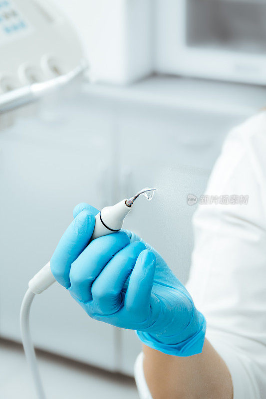 牙科超声刮水器。牙周超声标量。牙科仪器。鞑靼人。戴着蓝手套的牙医。