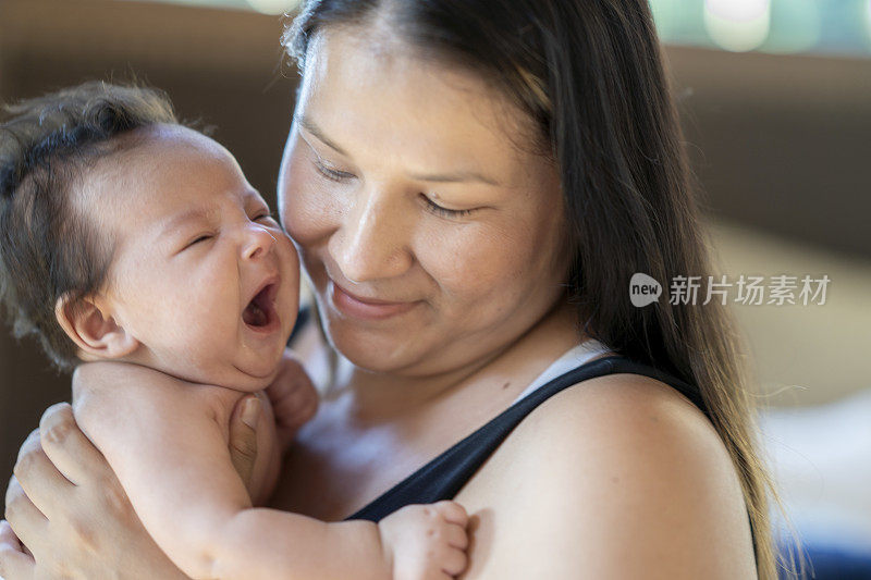 刚出生的女婴被妈妈抱着打哈欠