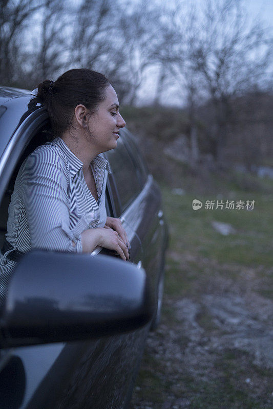 一个年轻女子站在车窗上，对着镜头摆姿势