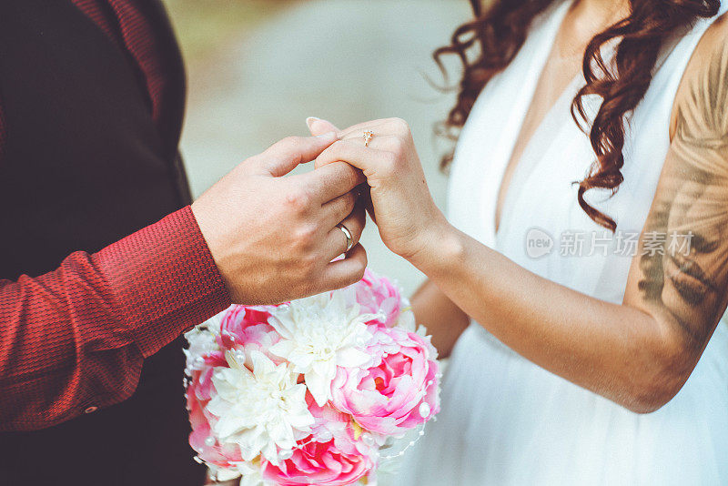 新郎手持结婚戒指握住新娘的手